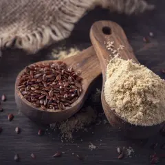 Dwie drewniane łyżki z siemieniem lnianym i mielonym siemieniem. Czy pies może jeść siemię lniane? Tak, w umiarkowanych ilościach.